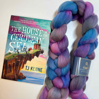 Hand-dyed spinning fiber braid in deep jewel tones with luminous depth, inspired by The House in the Cerulean Sea by T.J. Klune. Pictured with the book.
