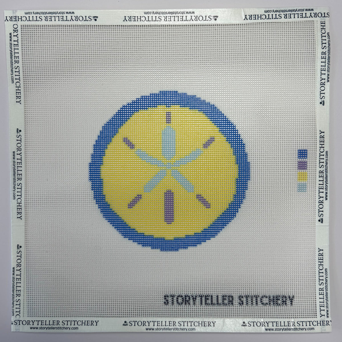 Needlepoint canvas with a blue and yellow sand-dollar design.